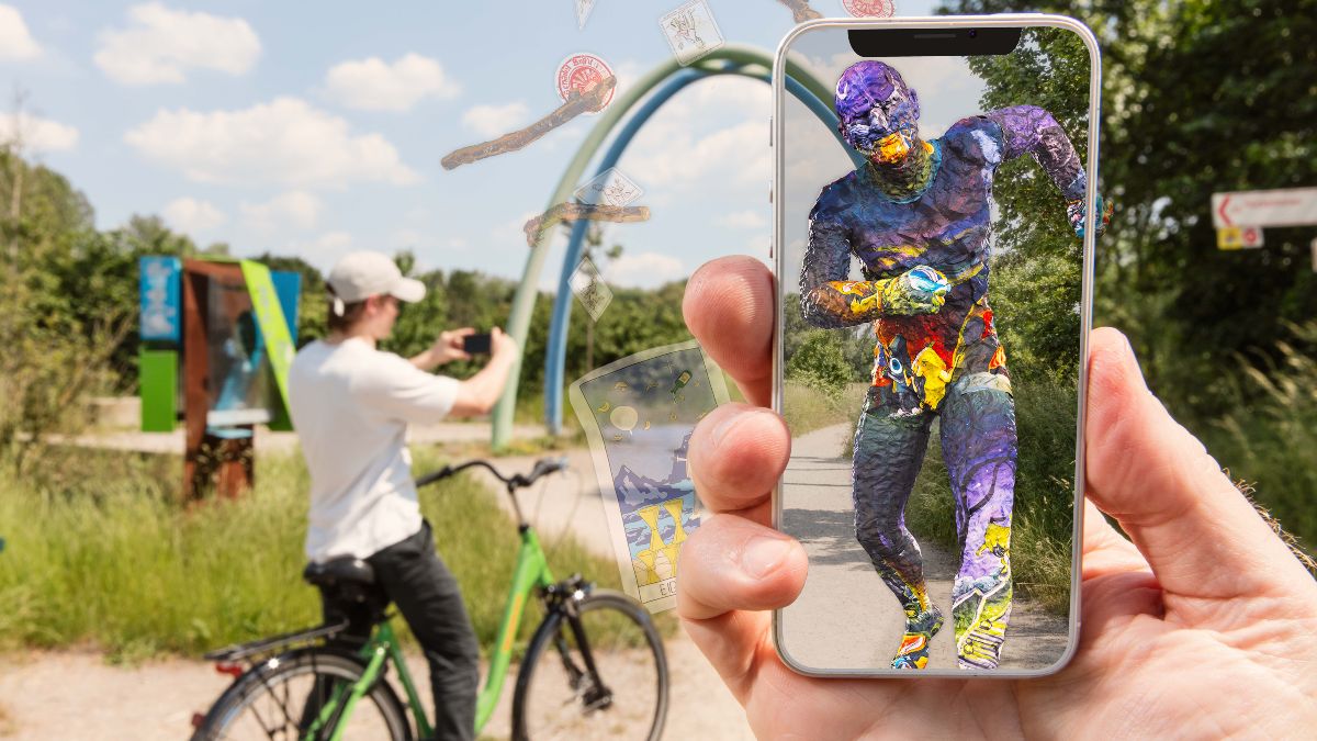 Spielplatz; davor Hand mit Smartphone, auf dessen Bildschirm virtuelle Zusatzinhalte zu sehen sind.